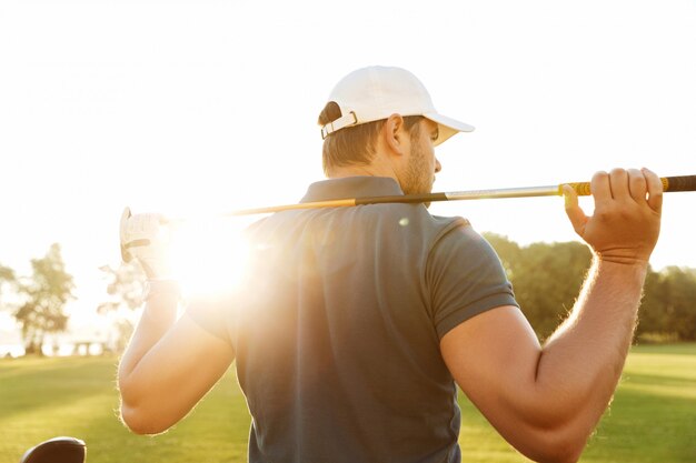 Widok z tyłu młodego człowieka, niosąc kij golfowy