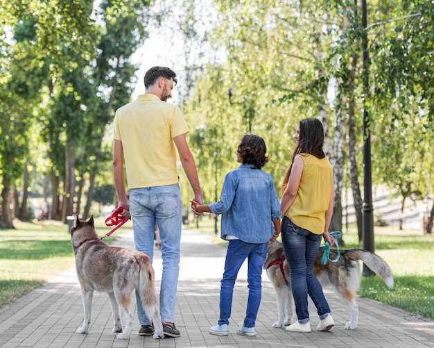 Bezpłatne zdjęcie widok z tyłu rodziny z dzieckiem i psami na świeżym powietrzu w parku