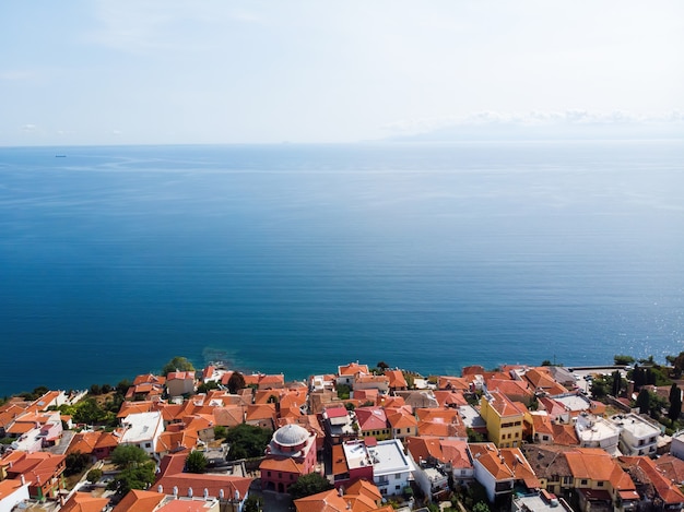 Wiele budynków z pomarańczowymi dachami, położonych na wybrzeżu Morza Egejskiego