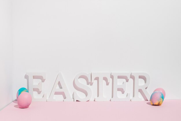 Wielkanocna inskrypcja z kolorowymi jajkami na stole