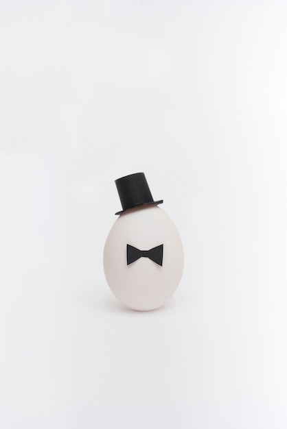 Bezpłatne zdjęcie wielkanocny jajko z łęku krawatem i kapeluszem na stole