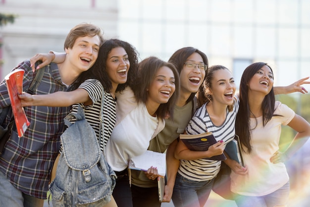 Wieloetniczna grupa młodych studentów szczęśliwy stojący na zewnątrz