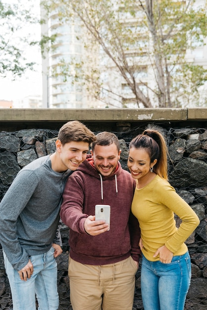 Wielorasowi przyjaciele bierze selfie blisko kamiennego ogrodzenia