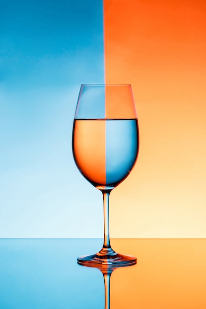 Wineglass z wodą na niebieskim i pomarańczowym tle.