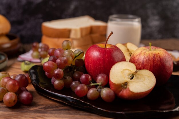 Winogrona, jabłka i chleb w talerzu na stole