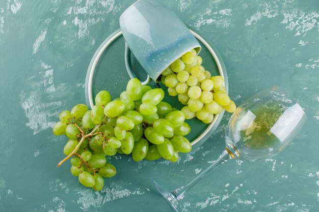 Winogrona w filiżance z napojem płasko leżały na tle tynku i tacy