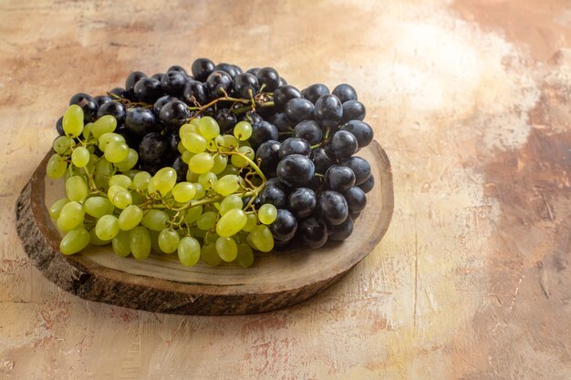 Winogrona widok z boku apetyczne czarne i zielone winogrona na drewnianej desce