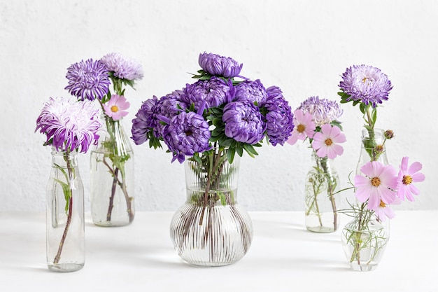 Wiosenna kompozycja z kwiatami chryzantem w szklanych wazonach na niewyraźne białe tło.
