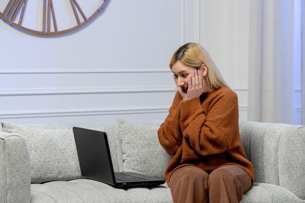 Wirtualna miłość ładna młoda blondynka w przytulnym swetrze na randkę z komputerem na odległość uśmiechnięta