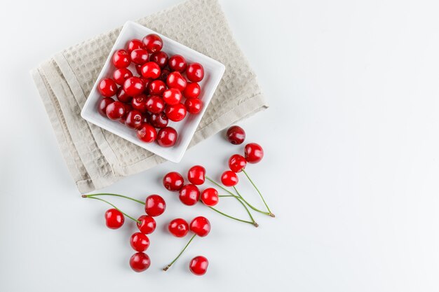 Wiśnie w talerzu na białym i kuchennym ręczniku