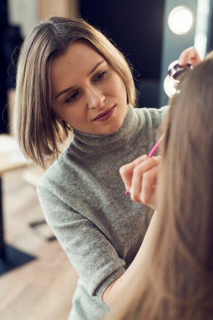 Wizażystka stosuje eyeliner na modelu upraw