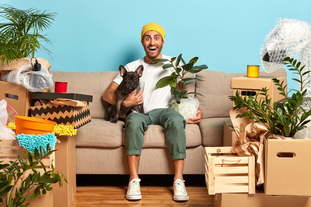 Wizerunek pozytywnego modnego faceta wynajmującego nowe mieszkanie, mieszka z ulubionym psem