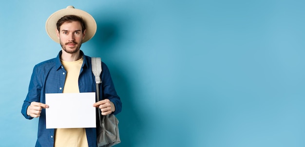 Bezpłatne zdjęcie wizerunek uśmiechniętego faceta w słomkowym kapeluszu podróżującego autostopem z kawałkiem papieru podróżującego za granicę na s
