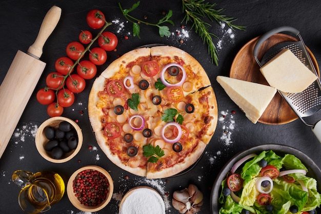 Włoska pizza i składniki do gotowania pizzy na ciemnej kamiennej powierzchni