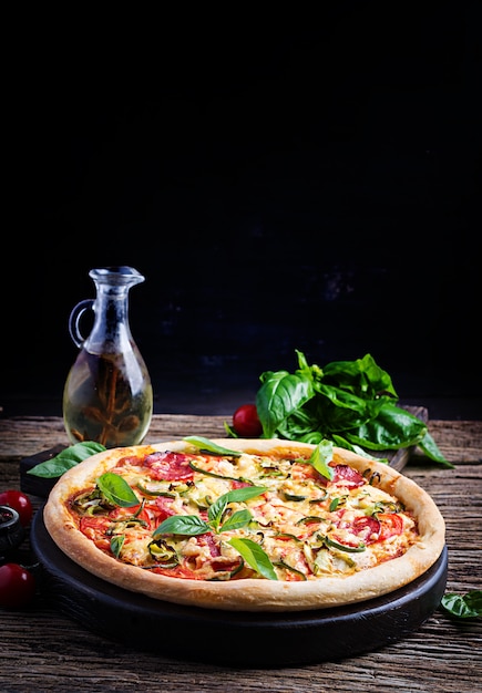Bezpłatne zdjęcie włoska pizza z kurczakiem, salami, cukinią, pomidorami i ziołami