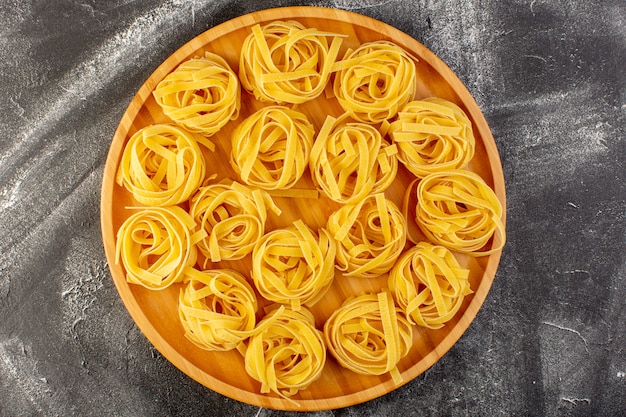 Włoski makaron w kształcie kwiatu w kształcie surowego i żółtego na drewnianym biurku w kształcie kwiatu włoskiego surowego jedzenia spaghetti