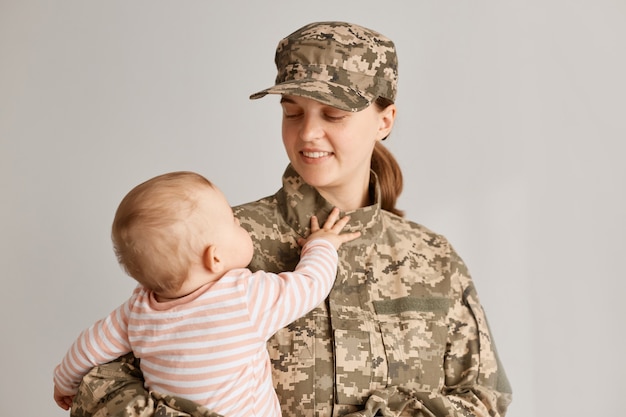 Wnętrze ujęcia szczęśliwej pozytywnej kobiety żołnierza wracającej do domu po wojsku, tęskniącej za swoją uroczą, czarującą córką, dziecka dotykającego matki, kobiety cieszącej się z powrotu do domu.