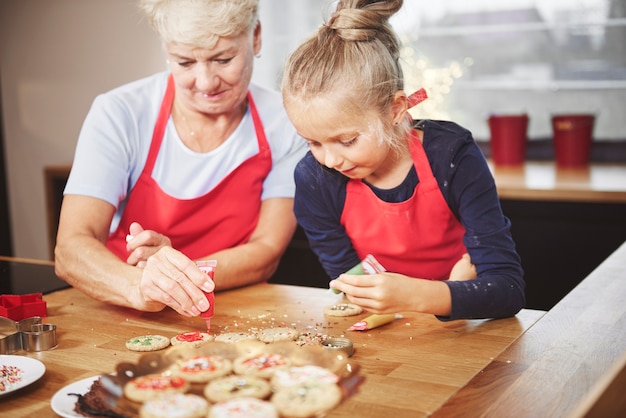 Wnuk z babcią dekoruje ciasteczka lukrem