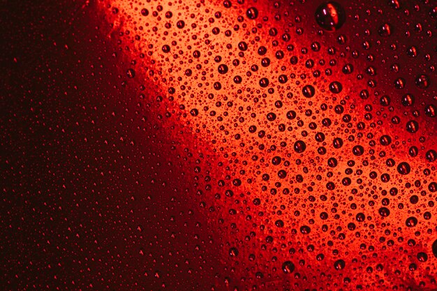 Woda opuszcza na szklanym czerwonym jaskrawym tle