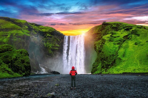 Wodospad Skogafoss na Islandii. Facet w czerwonej kurtce patrzy na wodospad Skogafoss.