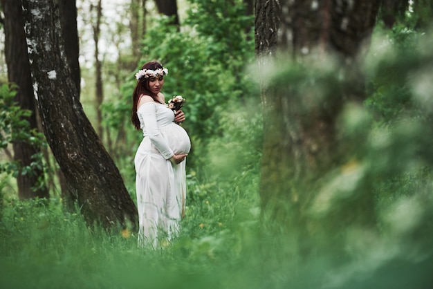 Bezpłatne zdjęcie wreszcie jest lato. piękna kobieta w ciąży w sukience na spacer na świeżym powietrzu. pozytywna brunetka