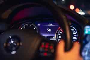 Bezpłatne zdjęcie wskazówka prędkości i ręce kobiety na kierownicy w samochodzie w nocy