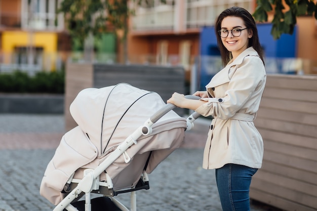 Wspaniała mama z wózkiem spaceruje w pobliżu parku