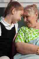 Bezpłatne zdjęcie wspieranie wnuczki dotykającej czoła starszej babci okazującej miłość podczas badania klinicznego...