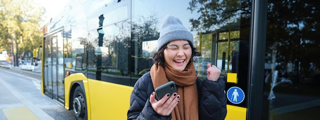 Współcześni ludzie i styl życia szczęśliwa azjatycka dziewczyna krzyczy z radości, świętując stoiska w pobliżu autobusu publicznego