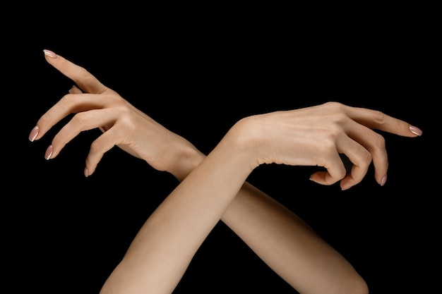 Wybór właściwej drogi. Męskie i kobiece dłonie, wykazując gest dotyku na białym tle na tle czarnego studia. Pojęcie relacji międzyludzkich, relacji, uczuć lub biznesu.