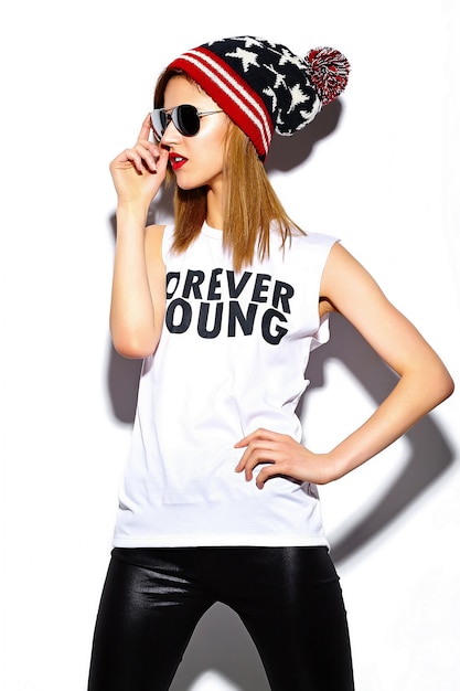Bezpłatne zdjęcie wygląd mody. glamour stylowy model piękna młoda kobieta z czerwonymi ustami w tkaniny hipster w okulary w kolorowe czapka