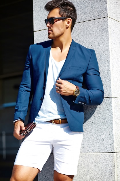 Bezpłatne zdjęcie wygląd mody. młody stylowy pewność szczęśliwy przystojny biznesmen model mężczyzna w niebieskim kolorze ubrania na ulicy w okulary przeciwsłoneczne