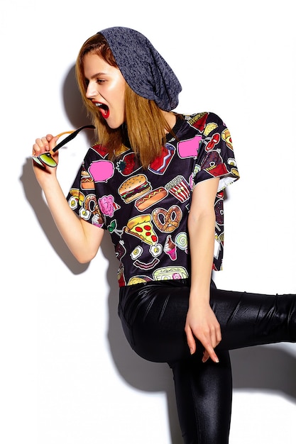 Wygląd mody. Seksowny stylowy model piękna młoda kobieta z czerwonymi ustami w tkaniny hipster w czapka dając znak Rock and Roll
