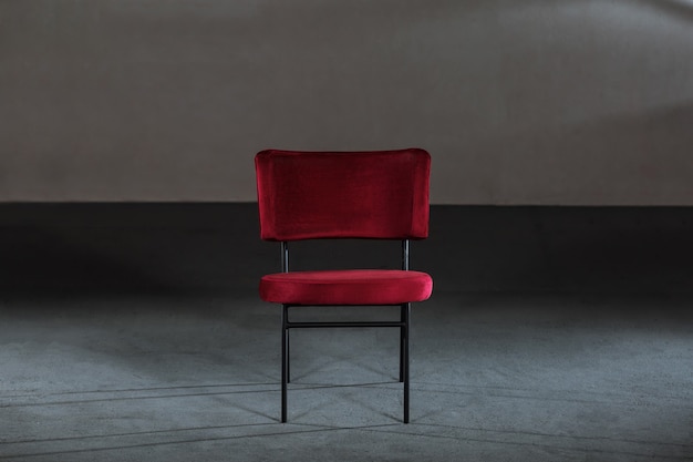 Wygodne czerwone krzesło skrzydłowe w pokoju z szarymi ścianami