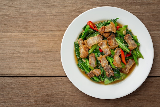 Bezpłatne zdjęcie wymieszaj smażony jarmuż, pikantną chrupiącą wieprzowinę na drewnianym stole. koncepcja tajskiego jedzenia.