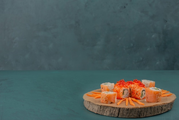 Bezpłatne zdjęcie wymieszaj sushi z plastrami marchewki na desce.