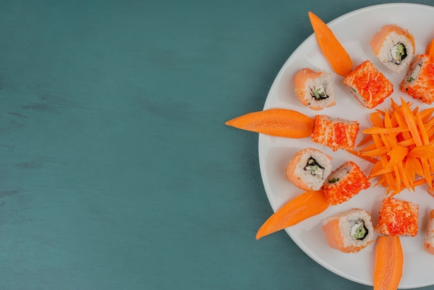 Wymieszaj sushi z plastrami marchwi na białym talerzu