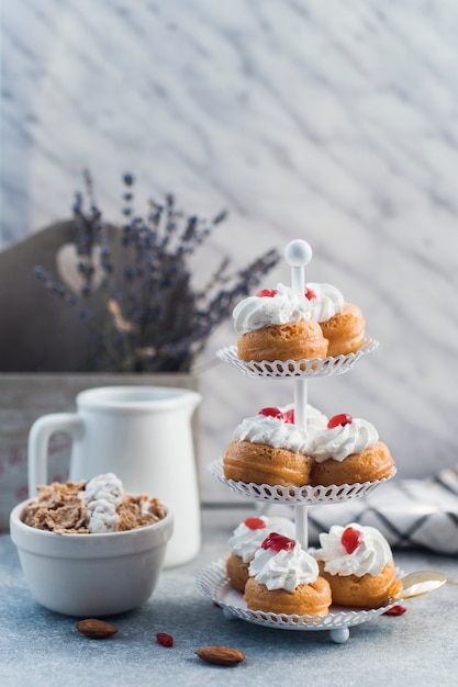 Wyśmienicie muffins na torta stojaku blisko pucharu płatki kukurydziane i migdał na betonowej powierzchni