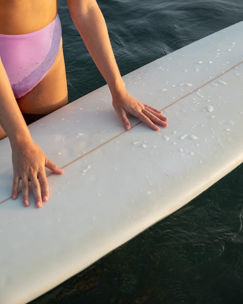 Bezpłatne zdjęcie wysoki kąt kobiety z deską surfingową na wodzie
