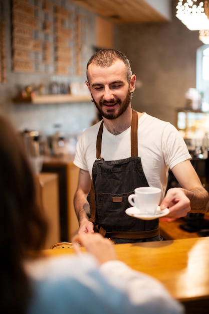 Wysoki kąt mężczyzna barista serwująca kawę