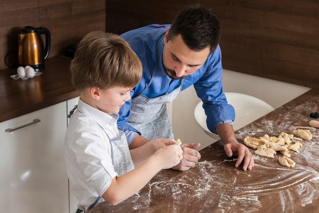 Bezpłatne zdjęcie wysoki kąt ojciec i syn, tworząc kształty ciasta