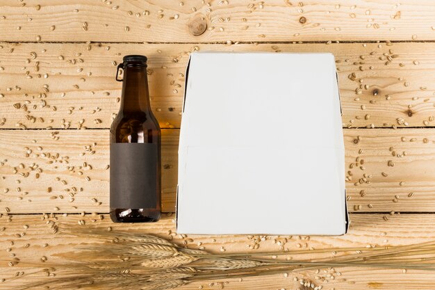 Wysoki kąt opakowania kartonowego; butelka piwa i kłosy pszenicy na drewniane deski