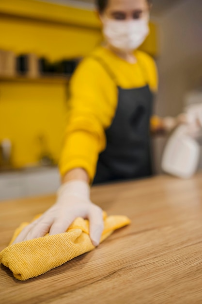 Wysoki kąt rozmytej powierzchni czyszczenia baristy podczas noszenia maski medycznej