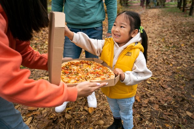 Wysoki kąt smiley dziewczyna trzyma pizzę