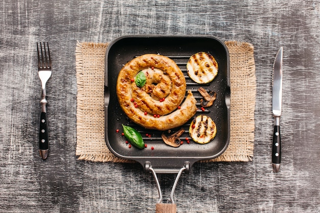 Wysoki kąt widzenia grillowane spiralne kiełbaski na patelni z nożem do widelca i masła