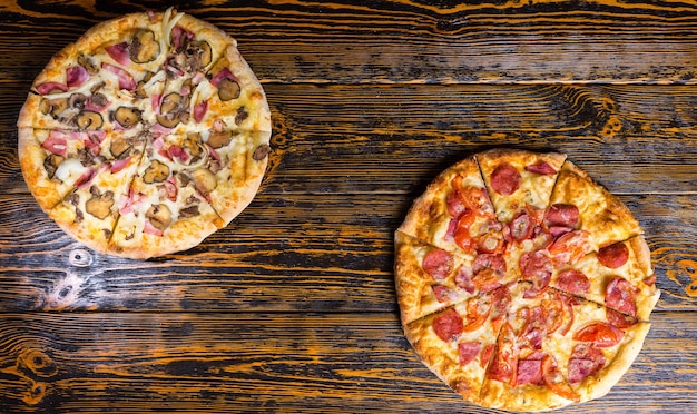 Wysoki kąt widzenia smacznych różnych pizzy z różnymi dodatkami i serem na drewnianym stole
