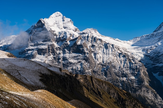 Wysokie skaliste góry pokryte śniegiem pod czystym, błękitnym niebem w Szwajcarii