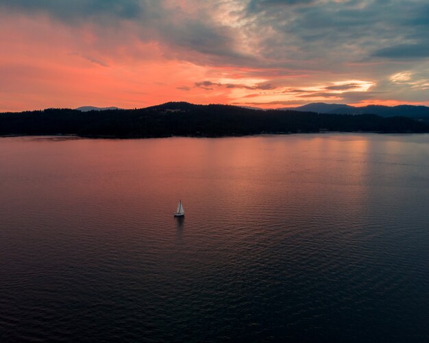 Wysokie ujęcie pięknego morza z pojedynczą łodzią płynącą o zachodzie słońca