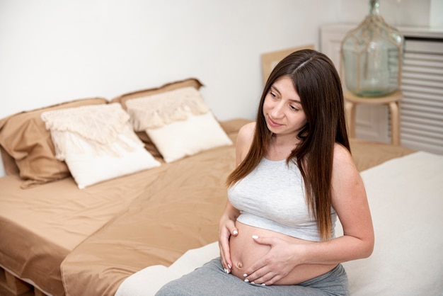 Wysokiego kąta kobieta w ciąży pozuje w sypialni