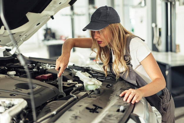 Wysokiego kąta mechanika żeński naprawiający samochód